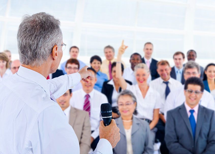 conference speaker at podium with large audience listening