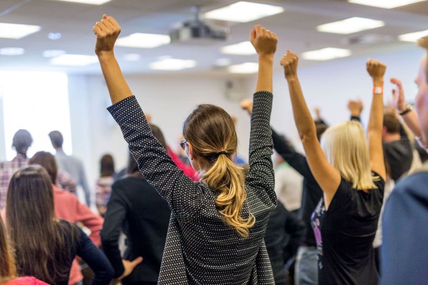 conference speaker at podium with large audience listening