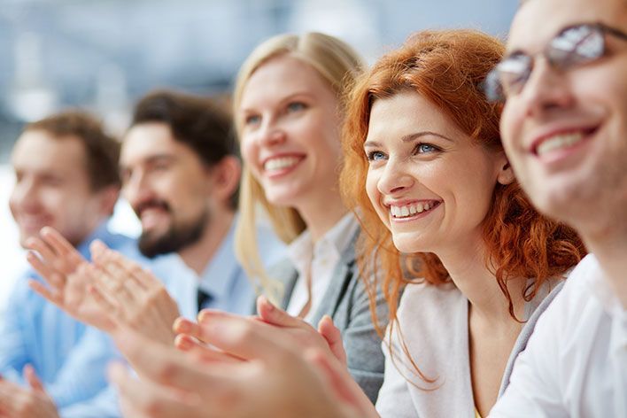 happy, smiling corporate meeting attendees applauding